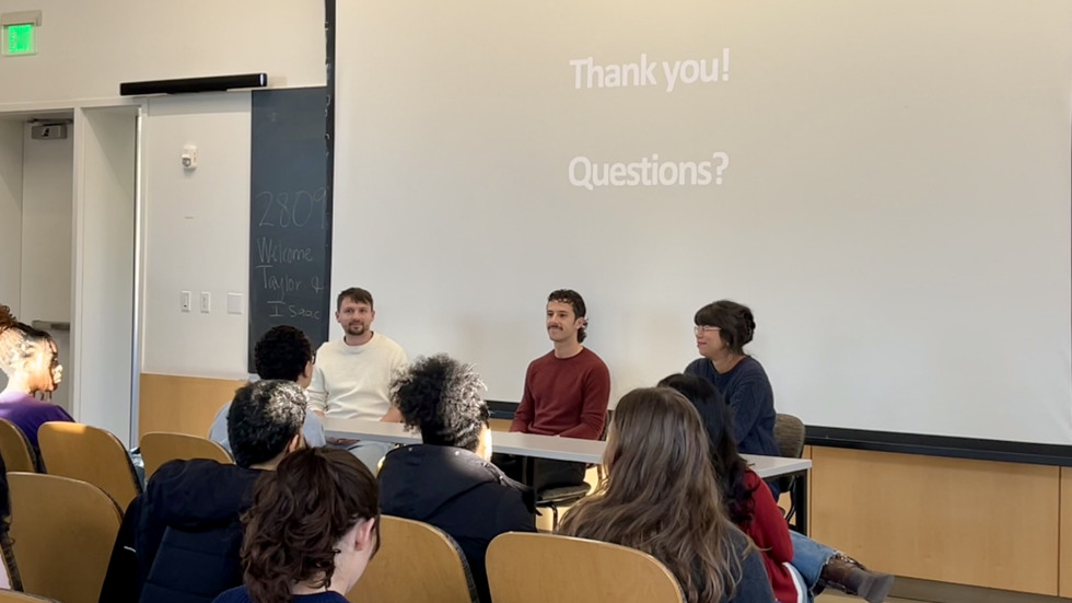 Three people sitting at a panel at the front of a classroom